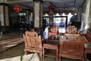 A lobby with traditional wooden furniture, a reception desk, and a view of the street outside.
