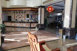 A hotel lobby with a reception desk, seating area, and a large red Chinese character decoration. - Pu'er Kunman Hotel (Pu'er)