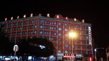 Un hotel de varios pisos con fachada roja y señalización iluminada.