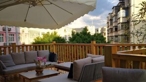 A wooden deck with outdoor furniture, including sofas and a table, under a large umbrella. - Pu'er Kunman Hotel (Pu'er)