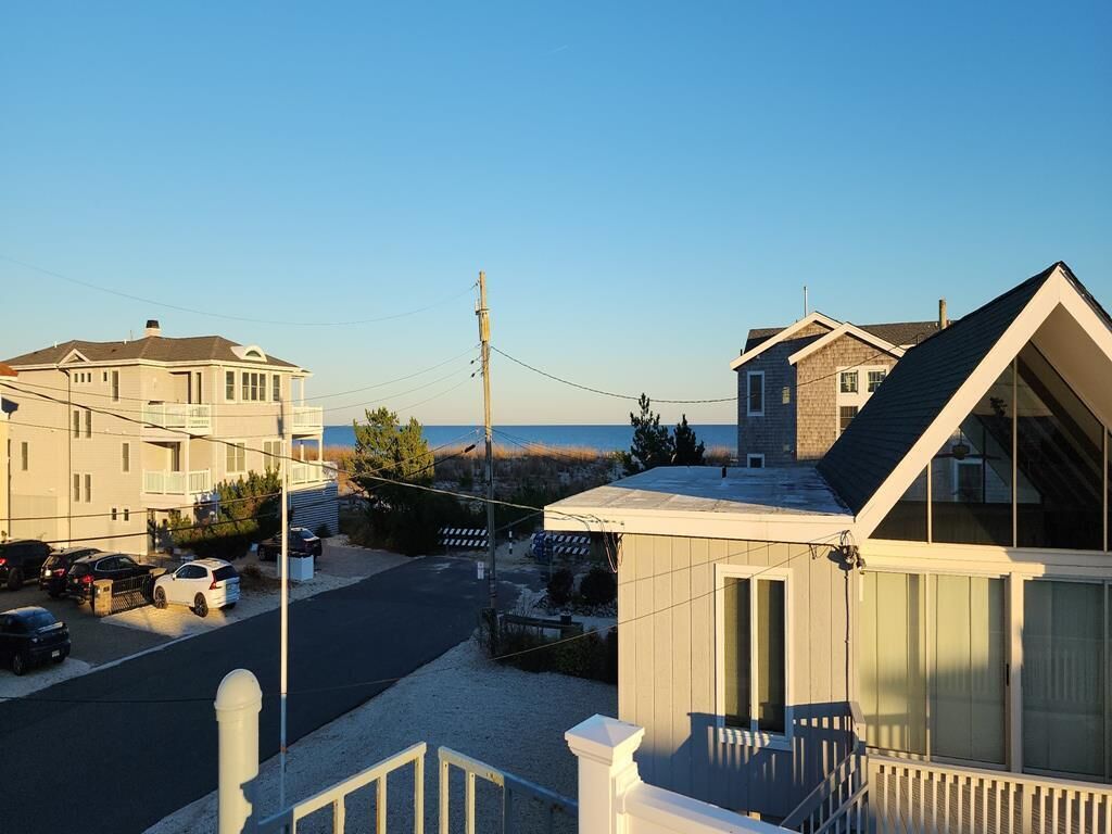 A residential street with houses, a clear sky, and a view of the beach.