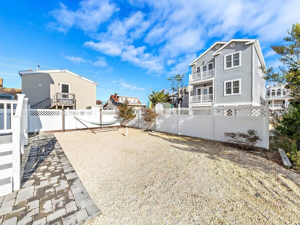 A residential area with a gravel driveway, white fences, and houses with balconies.