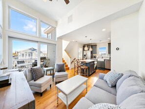 A spacious living area with a large window, a kitchen with a central island, and a staircase leading to an upper level.