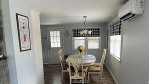 A dining area with a round table, chairs, a chandelier, and a door with a window.