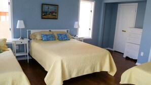 A bedroom with a bed, two bedside tables, a nightstand, a dresser, and a painting on the wall.