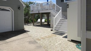 A residential property with a covered patio, a staircase leading to a deck, and a garage.