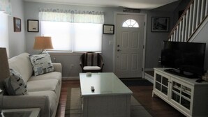 A living room with a sofa, a coffee table, a television, and a staircase.