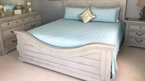 Ein Schlafzimmer mit Bett, Kommode, Nachttisch und Spiegel.