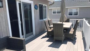 Eine Terrasse mit Tisch und Stühlen, einer Schiebetür aus Glas und einem Sonnenschirm.