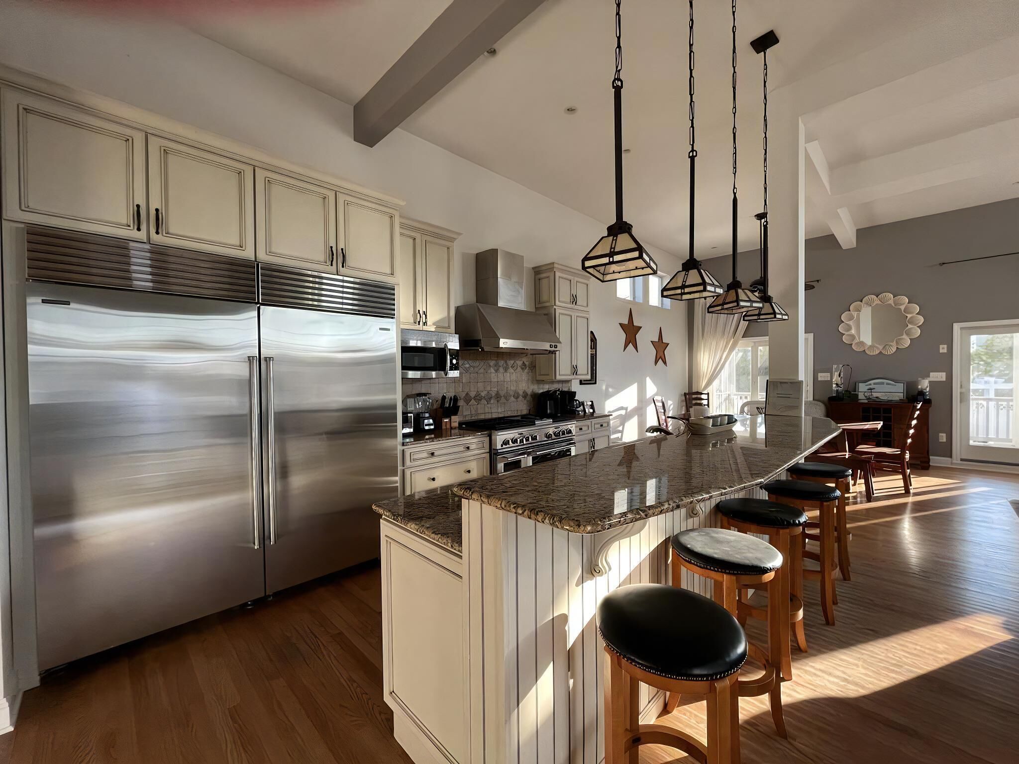A modern kitchen with stainless steel appliances, a central island with bar stools, and pendant lighting.