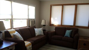 A living room with two brown sofas, a striped rug, a lamp, and a window with blinds. - Beautiful apartment in Barnegat Light with 2 Bedrooms and WiFi (Barnegat Light)
