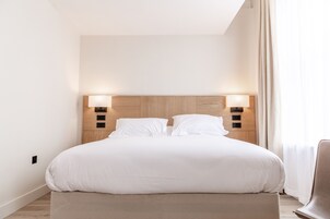 Una cama bien hecha con cabecera de madera y dos lámparas de noche.