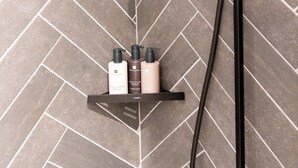 Een douche met een modern ontwerp, inclusief een regendouche en een handdouche, gemonteerd op een wand met een mozaïek van ruitjes.