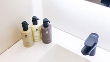 A bathroom sink with three bottles of skincare products and a modern faucet.
