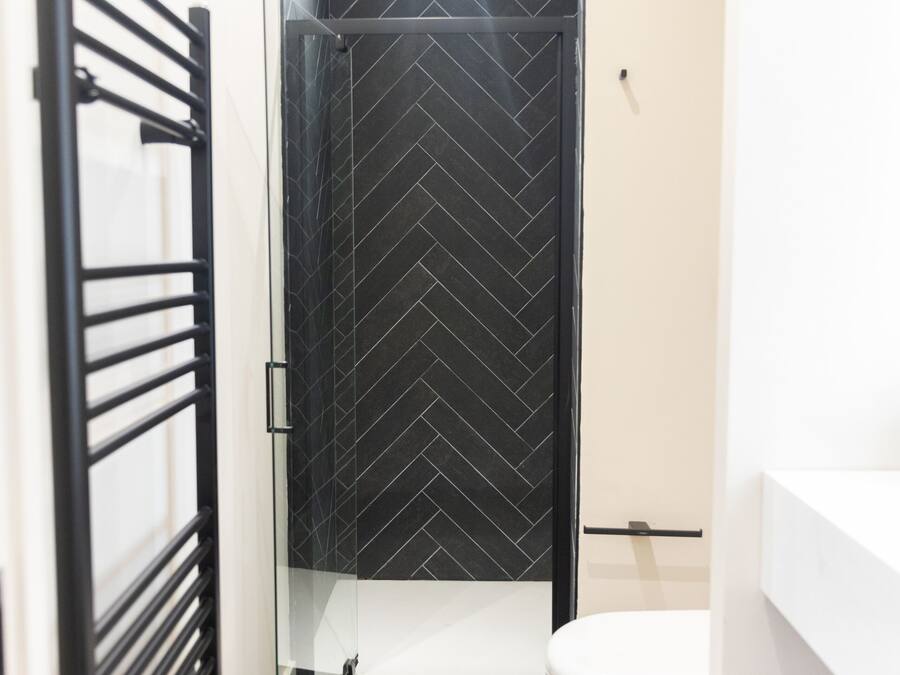 A modern bathroom with a glass shower enclosure, a white toilet, and a grey floor.