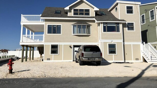 A multi-story house with a garage, a balcony, and a driveway.