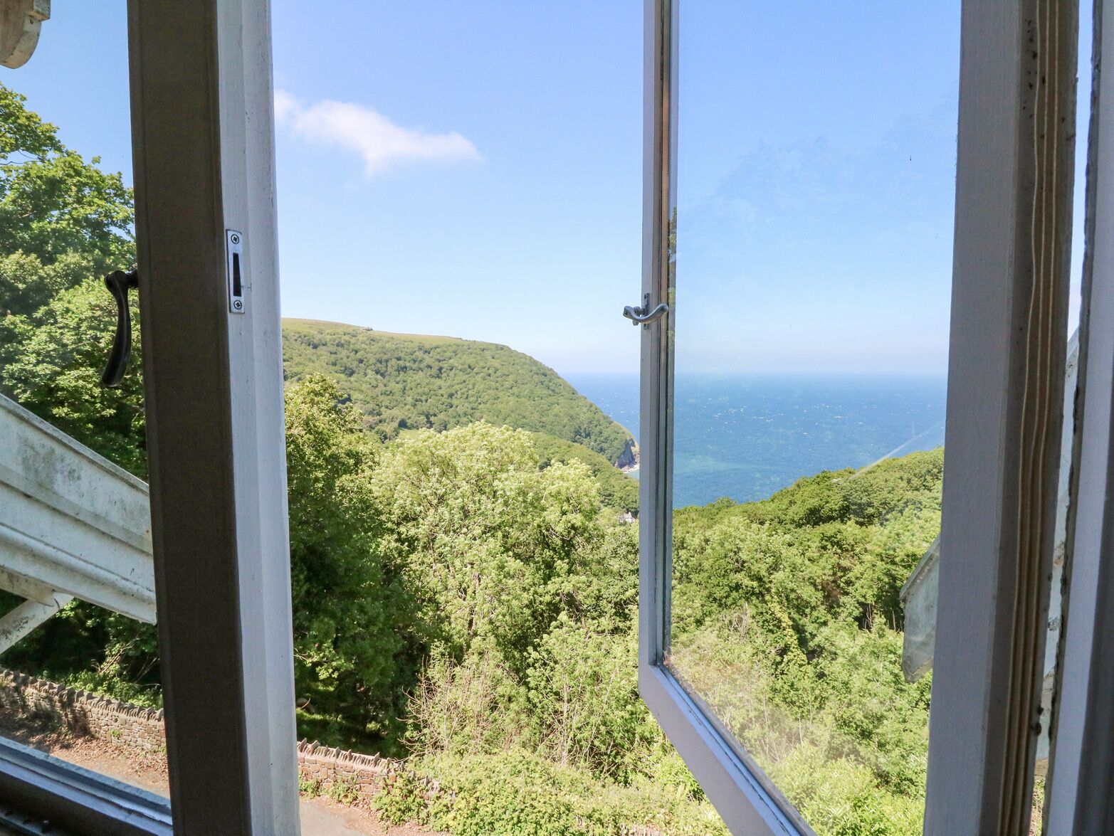 A window view of a lush green landscape with a clear sky.
