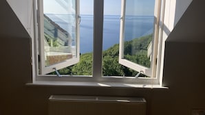 Una habitación con un amplio ventanal que ofrece vistas al mar y al verdor.