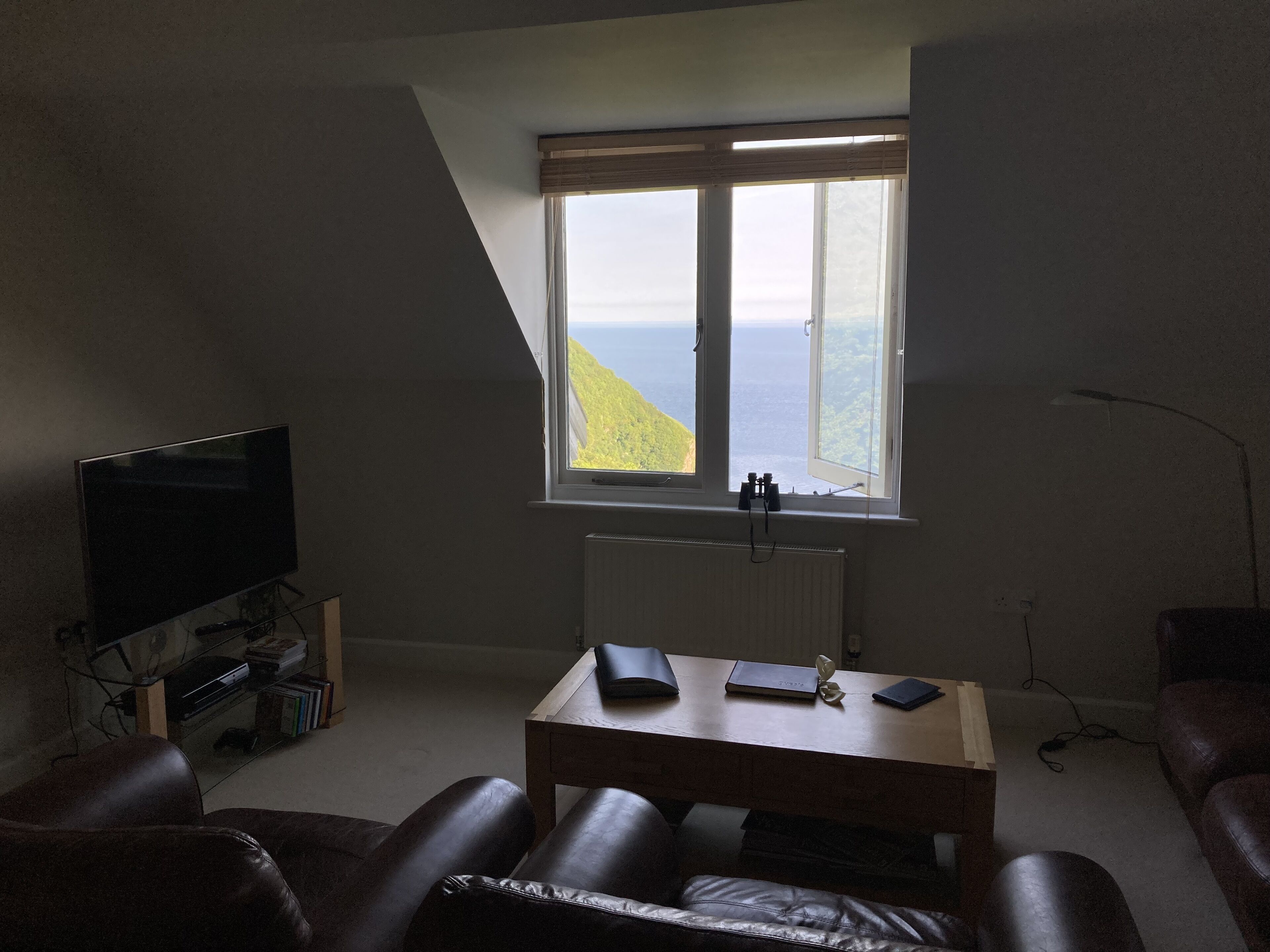 Una habitación con televisión, una mesa, un ventanal con vista al mar y un radiador.