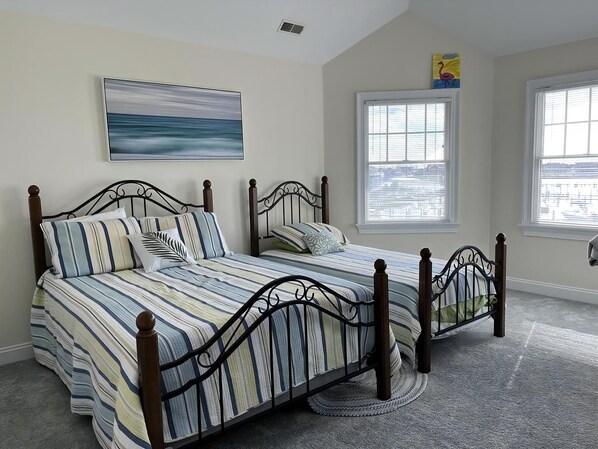 Une chambre avec un lit double, une fenêtre avec des stores, un tableau au mur et un sol recouvert de moquette.