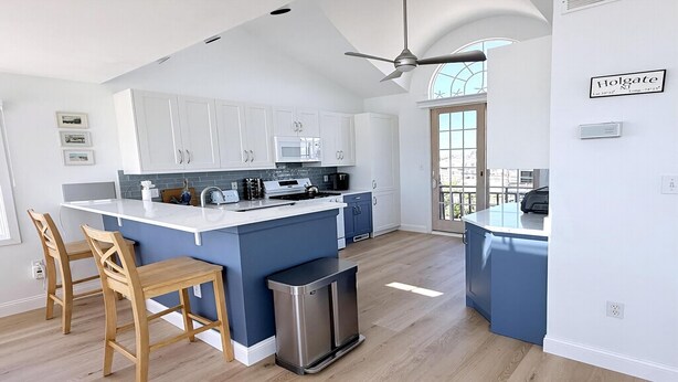 A modern kitchen with white cabinets, a blue island, and a stainless steel trash can. - 3 bedroom accommodation in Holgate (Holgate)