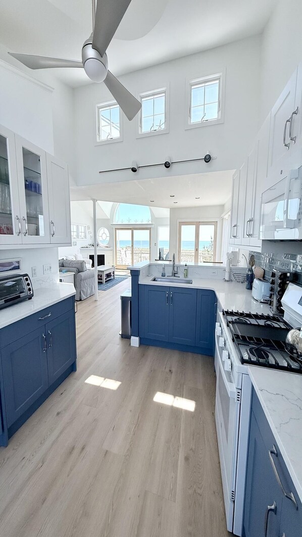 A spacious kitchen with a central island, a ceiling fan, and a view to the outside.