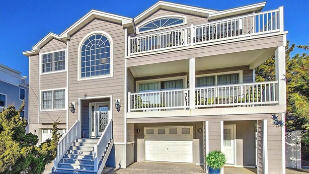 A two-story house with a front staircase, a garage, and a balcony. - Ocean views- luxurious vacation rental on LBI (Brant Beach)