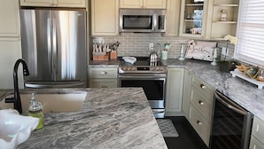 A kitchen with stainless steel appliances, marble countertops, and light-colored cabinetry. - Ocean views- luxurious vacation rental on LBI (Brant Beach)