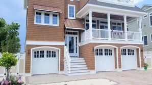 Ein mehrstöckiges Haus mit Veranda, Garage und Balkon.