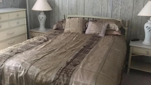 A bedroom with a bed, two nightstands, a dresser, and two lamps.
