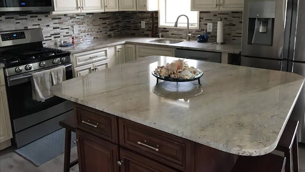 A modern kitchen with white cabinets, a stainless steel refrigerator, a microwave, and a stove.
