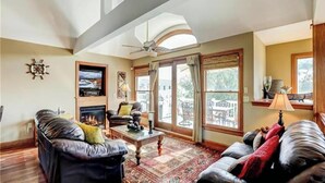 Ein Wohnzimmer mit Kamin, Ledersofas, einem Couchtisch und großen Fenstern.