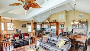 Ein geräumiges Wohnzimmer mit einem großen Ledersofa, einem Couchtisch und einem Deckenventilator.