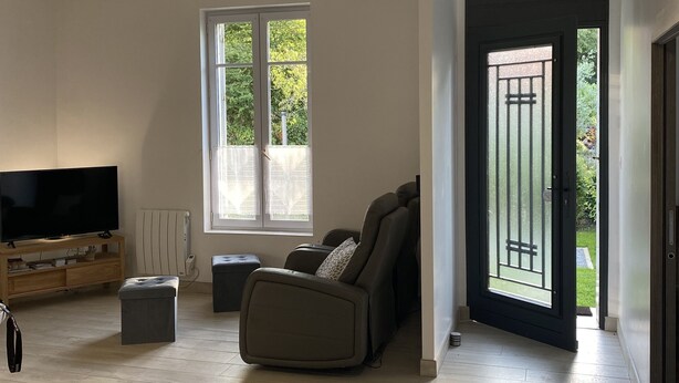 A spacious living room with a flat-screen TV, a sofa, and a large window.