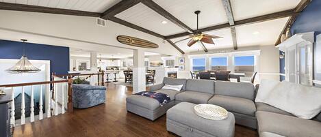 A spacious living area with a high ceiling, wooden beams, and a large window overlooking a scenic view.
