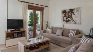 Een woonkamer met een televisie, een salontafel, een bank en een schilderij van een paard.