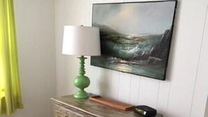 Ein Zimmer mit einem hölzernen Schminktisch, einer grünen Lampe und einem Meeresblick-Gemälde an der Wand.