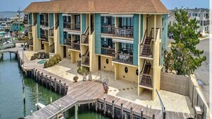 Un hotel a più piani con balconi, un pontile e uno yacht club sullo sfondo.