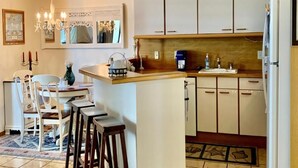 Una cucina moderna con isola centrale, sgabelli da bar e zona pranzo con sedie e tavolo.