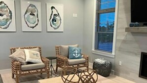 A modern living room with a sofa, two wicker chairs, a coffee table, and a fireplace. - BEAUTIFUL LAGOON FRONT 5 BEDROOM HOME (High Bar Harbor)