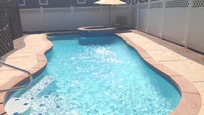 A rectangular swimming pool with a hot tub, surrounded by a white fence and a patio area. - Beautiful Private Ocean Front Home (Loveladies)