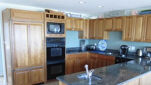 A kitchen with wooden cabinets, a built-in microwave, a double oven, a granite countertop, and a sink. - Beautiful Private Ocean Front Home (Loveladies)