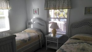 A bedroom with two single beds, a nightstand with a lamp, a window with blinds, and a wall-mounted star decoration. - Amazing apartment in Barnegat Light with 3 Bedrooms and WiFi (Barnegat Light)