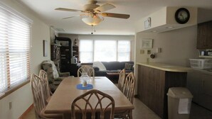 A dining area with a table, chairs, a ceiling fan, and a kitchen area with a counter and cabinets. - Stunning home in Ship Bottom with 4 Bedrooms and Internet (Ship Bottom)