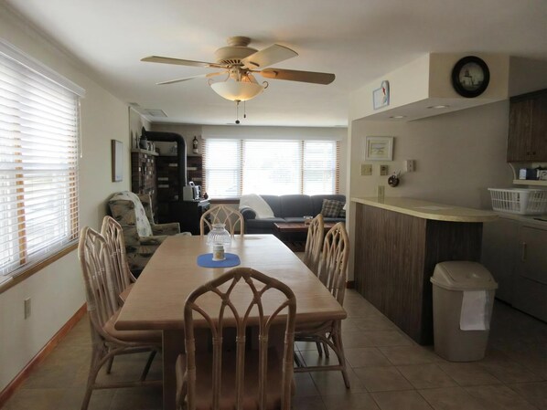 A dining area with a table, chairs, a ceiling fan, and a kitchen area with a counter and cabinets.