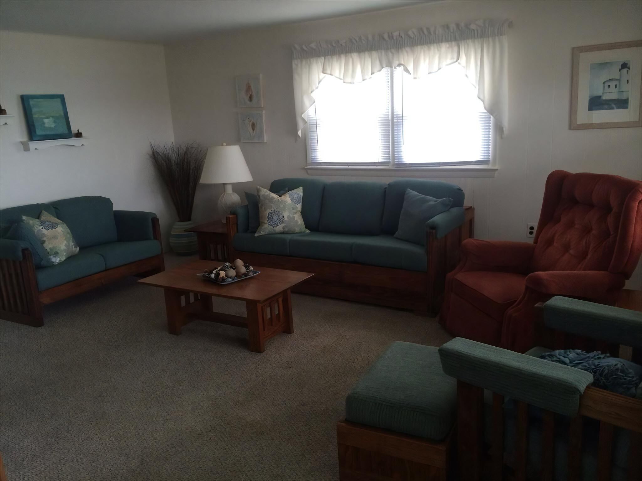 A living room with a sofa, armchair, coffee table, and a lamp.