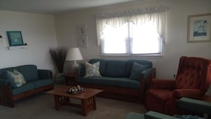 A living room with a sofa, armchair, coffee table, and a lamp. - Outstanding Bayviews from this 1st floor duplex (Surf City)