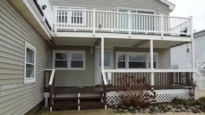 A two-story house with a balcony, a front porch, and a small garden area with rocks and plants. - Outstanding Bayviews from this 1st floor duplex (Surf City)