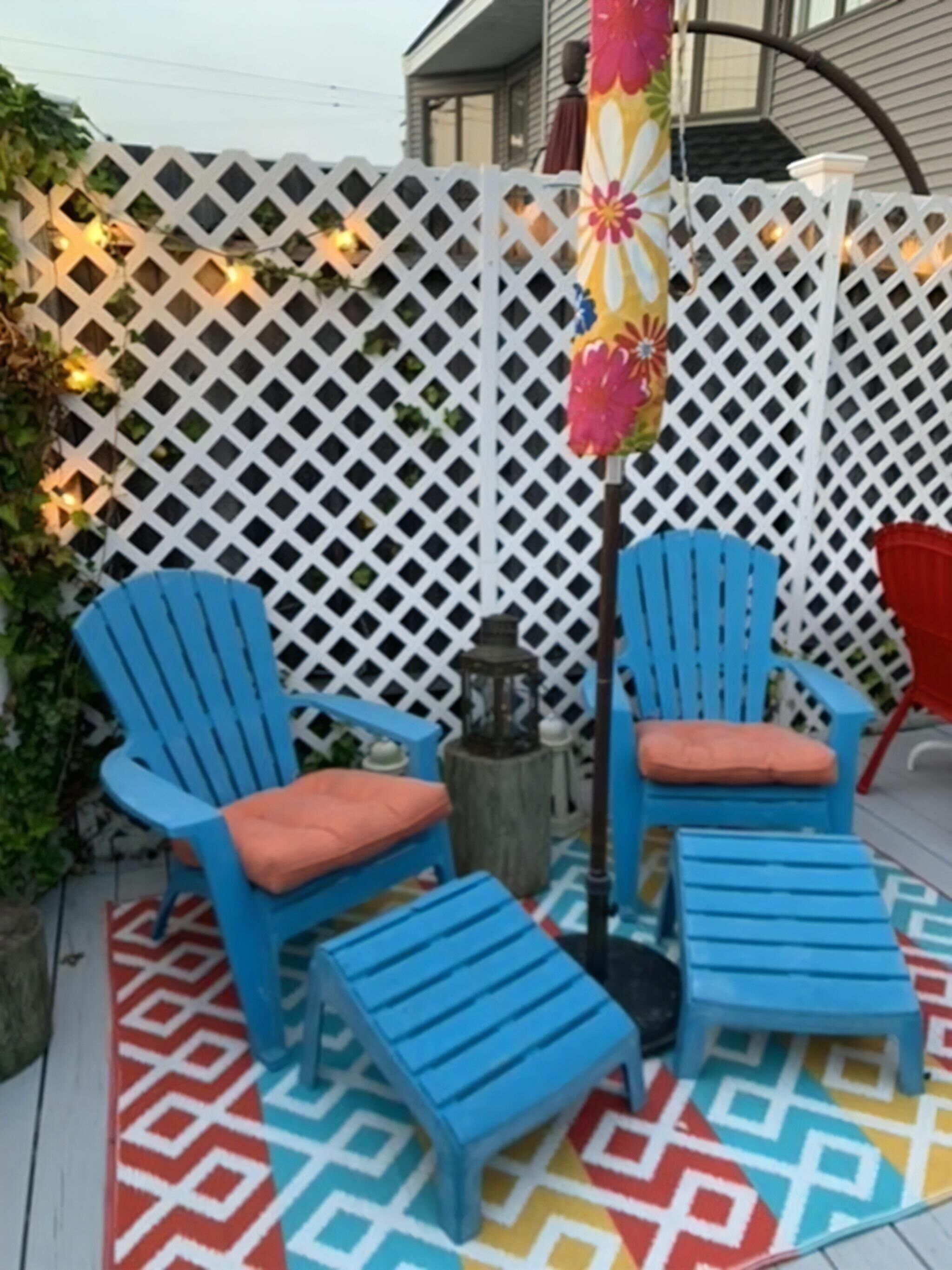 A patio with blue Adirondack chairs, a small table, and a decorative post.