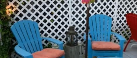 A patio with blue Adirondack chairs, a small table, and a decorative post.